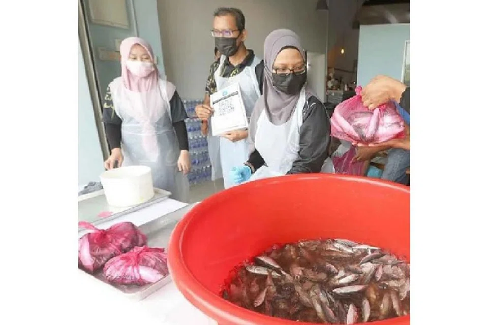 IKAN AMAL: Setiausaha NGO Dapur Infaq Ummah, Encik Zahir Shah Zahid (dua dari kiri), membantu menjual ikan selayang segar pada harga 20 sen Malaysia seekor di Kuantan bagi membantu keluarga terjejas Covid-19. - Foto NSTP