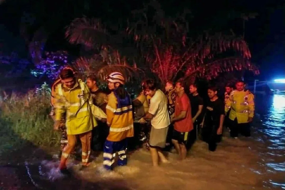 Anggota bomba dan orang ramai melakukan kerja menyelamat mangsa banjir di Johor.