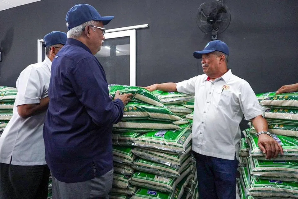 TINJAU BEKALAN: Menteri Pertanian dan Keterjaminan Makanan, Datuk Seri Mohamad Sabu (kanan), meninjau bekalan beras tempatan pada Program Jualan Agro Madani di Pertubuhan Peladang Kebangsaan Pokok Sena, Kedah pada Rabu.