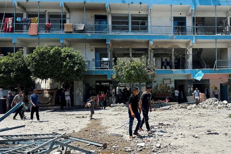 Penduduk Palestin meninjau tapak serangan Israel ke atas sekolah UNRWA yang melindungi orang yang kehilangan tempat tinggal, di kem pelarian Nuseirat di tengah Jaluran Gaza pada 6 Jun.