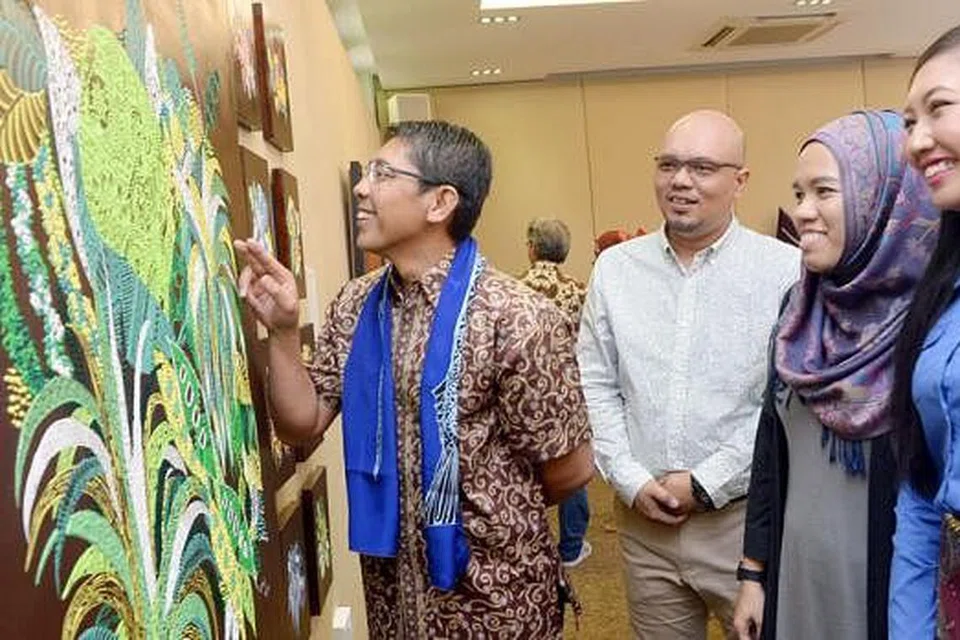 TELITI SENI: Dr Mohd Maliki (kiri) meninjau karya dua artis muda berbakat Cik Nurul Jannah Naharuddin (bertudung) dan Cik Nurul Munawwarah Muhd Rashidi. 