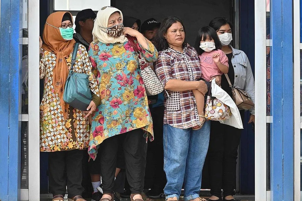 LANGKAH BERJAGA-JAGA: Sekumpulan warga Indonesia, kebanyakannya menggunakan pelitup, sedang menunggu bas di perhentian bas di Jakarta. Dewan Perwakilan negara menggesa pemerintah melaksana langkah pencegahan lebih tegas bagi menangani penularan Covid-19 di negara itu. - Foto AFP
