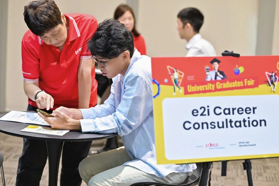 Seorang jurulatih kerjaya NTUC e2i memberi panduan kepada seorang pencari kerja muda di Pameran Kerjaya Siswazah Universiti pada 15 Ogos. 