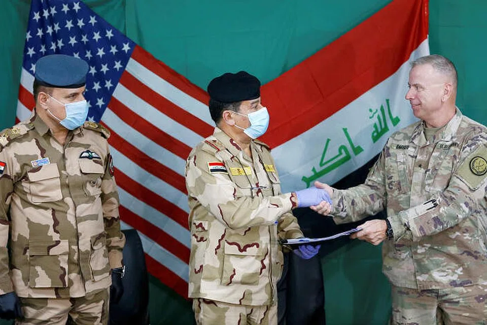 KERJASAMA TENTERA DUA NEGARA: Panglima tentera Amerika Syarikat, Brigadier Jenderal Vincent Barker (kanan), berjabat tangan dengan Panglima Tentera Iraq, Jeneral Mohammed Fadel (tengah), memakai pelitup dan sarung tangan, berikutan wabak penyakit koronvavirus, semasa penyerahan pangkalan tentera udara di barat Qayyarah, dari gabungan tentera pimpinan Amerika Syarikat ke Pasukan Keselamatan Iraq, di selatan Mosul, Iraq, pada 26 Mac lalu.