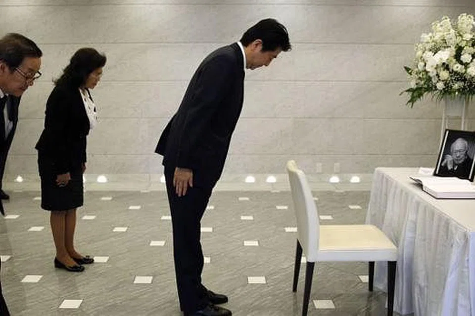 BERI PENGHORMATAN: Perdana Menteri Jepun, Encik Shinzo Abe (kanan), dengan Duta Singapura ke Jepun, Encik Chin Siat Yoon (kiri), dan isterinya, Cik Wang Lee Moi, sama-sama memberi penghormatan kepada mendiang Encik Lee di Kedutaan Singapura di Tokyo. - Foto AFP