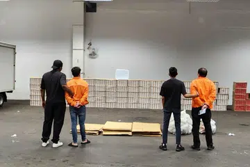 PADAH ELAK CUKAI: Dua lelaki ini (berpakaian oren) ditangkap dan 3,550 karton rokok tidak dibayar cukai serta sebuah trak dan sebuah van yang digunakan dalam kegiatan melibatkan barang elak cukai dirampas Kastam Singapura dalam satu operasi pada 2 Februari. - 