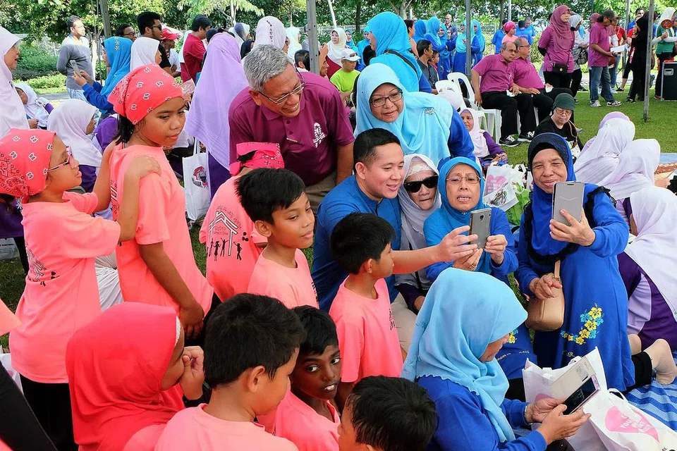 GAYA HIDUP SIHAT: Peserta acara berjalan kaki beramai-ramai amal Pertapis mengambil kesempatan beramah mesra dan bergambar bersama Encik Amrin (tengah, berbaju biru) di Woodlands Waterfront di Admiralty Road West, kelmarin. - Foto KHALID BABA