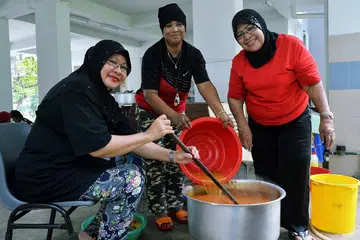 SEMANGAT SUKARELAWAN SEJATI: Cik Jainah Awang (kanan) berasa gembira setiap kali membantu memasak bagi penduduk Blok 3 dan 4 Marsiling Drive, tanpa mengira bangsa atau agama, setiap Jumaat bersama beberapa sukarelawan lain di kawasan itu. - Foto KHALID BABA
