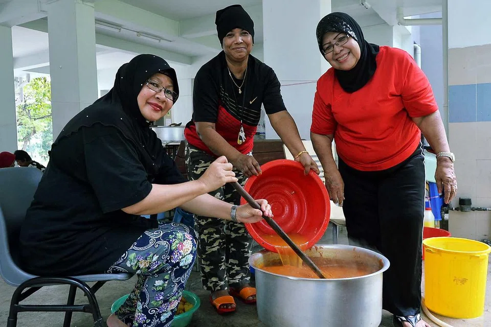 SEMANGAT SUKARELAWAN SEJATI: Cik Jainah Awang (kanan) berasa gembira setiap kali membantu memasak bagi penduduk Blok 3 dan 4 Marsiling Drive, tanpa mengira bangsa atau agama, setiap Jumaat bersama beberapa sukarelawan lain di kawasan itu. - Foto KHALID BABA