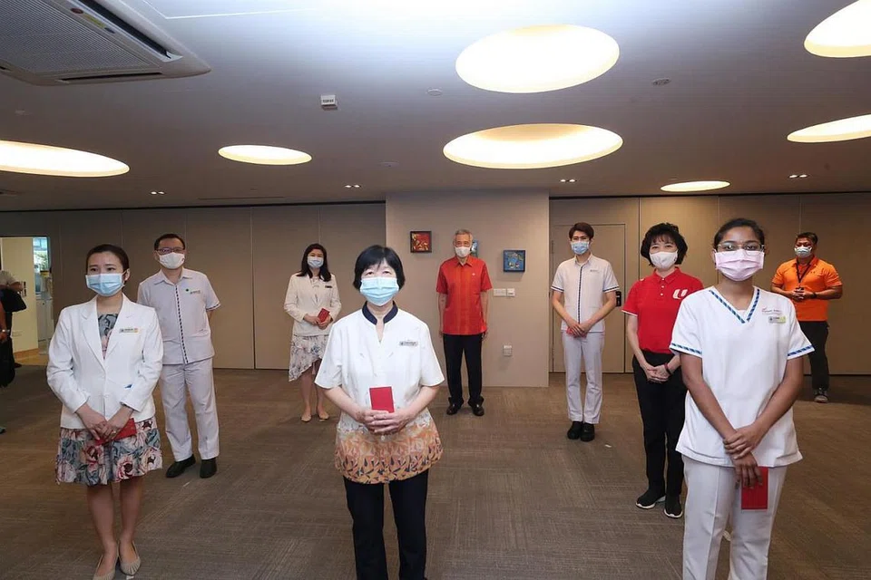 Encik Lee (belakang, berbaju merah) bersama presiden NTUC Mary Liew (tiga dari kanan) bersama kakitangan CGH.