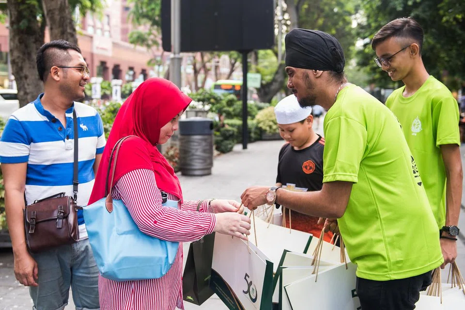 TURUT TURUN PADANG: Gurpinderjeet Singh dan Hudzaimi Mohd Dollah mendekati antara pengunjung di Orchard Road untuk mengedarkan risalah dan menerangkan tentang kempen Sentuhan Ramadan. - Foto BH oleh LIN ZHAOWEI