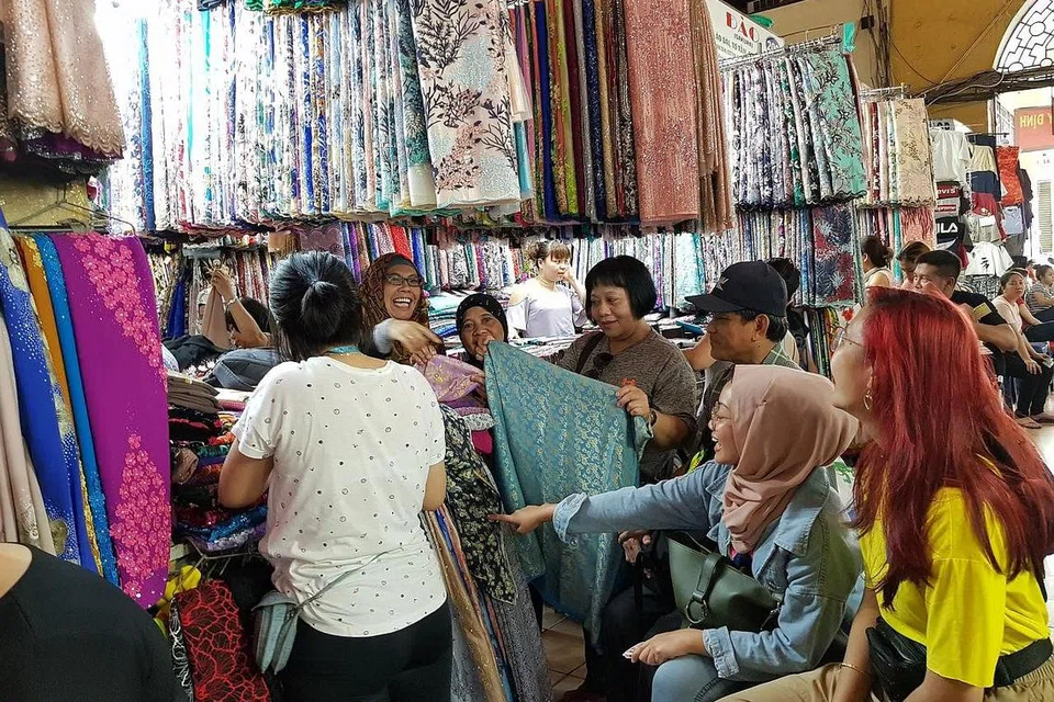 RAMBANG MATA: (Dari kiri) Cik Kamissah, Cik Norliah, Cik Sekrah, Encik Tahir, Cik Nur Syazwani dan Cik Aqilah memilih kain untuk ditempah dan dijahit siap pada keesokan harinya. Pakaian itu akan digayakan Lebaran nanti. - Foto BH oleh NIZAM ISMAIL