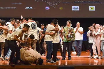 GEMBIRA TIDAK TERHINGGA: Anggota kumpulan dikir barat Temasek Politeknik, PST JE, tidak dapat menahan rasa gembira selepas muncul juara keseluruhan Piala Suara Serumpun dan menerima trofi yang disampaikan tetamu terhormat, Dr Faishal Ibrahim (berbaju batik hijau). - Foto POLITEKNIK TEMASEK