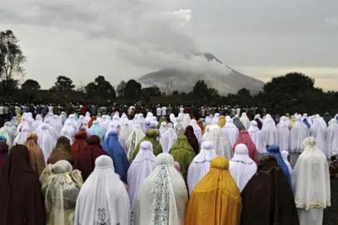 MENGAGUNGKAN TUHAN PENCIPTA ALAM SEMESTA: Penduduk kampung Ndokum Siroga di Karo, Sumatera Utara, yang tinggal di kaki gunung berapi Sinabung, menunaikan solat Aidilfitri berlatarbelakangkan kepulan asap yang terbit daripada gunung tersebut, kelmarin. - Foto REUTERS