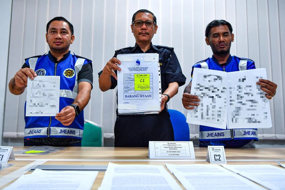 Ketua Unit Operasi Bahagian Penguatkuasaan Jabatan Hal Ehwal Agama Islam Negeri Sembilan (JHEAINS), Encik Ahmad Zaki Hamzah (tengah), bersama pegawainya menunjukkan rampasan dokumen pada sidang media mengenai tangkapan melibatkan pengikut ajaran The Ahmadi di Pusat Dakwah Islamiah Paroi, Negeri Sembilan, pada 23 Oktober.