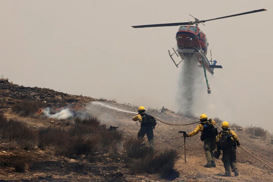 Sebuah helikopter dilihat mengggurkan air sedang para anggota bomba giat memadamkan api di New Cuyama, California, Amerika Syarikat, pada 3 Julai 2025. 
