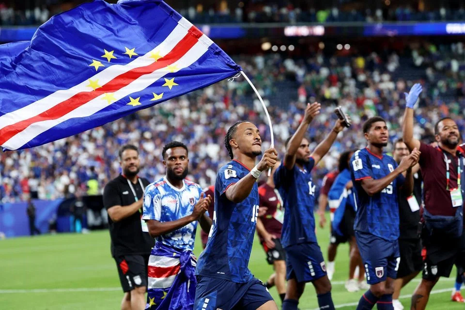 Pemain Cape Verde, Dailon Livramento (dua dari kiri), mengibar bendera negaranya ketika meraikan kelayakan ke peringkat kalah mati Piala Dunia 2026 buat julung-julung kalinya, setelah mengikat Arab Saudi 0-0 pada 27 Jun di Stadium Houston.