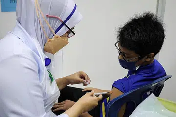 VAKSINASI BAGI GOLONGAN REMAJA: Seorang pelajar sekolah menengah menerima vaksinasi Covid-19 di sebuah sekolah di Putrajaya baru-baru ini. - Foto REUTERS