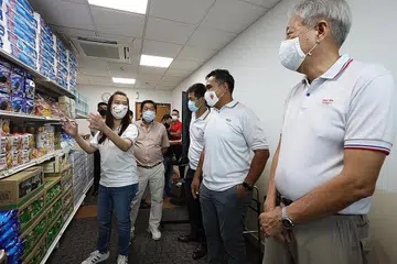 DAPATKAN BARANGAN KEPERLUAN: Encik Sharael (dua dari kanan) bersama Encik Teo (paling kanan) dan Encik Tan (tiga dari kanan) mengunjungi Pasir Ris Care Store semalam. - Foto PERTUBUHAN AKAR UMBI PASIR RIS EAST