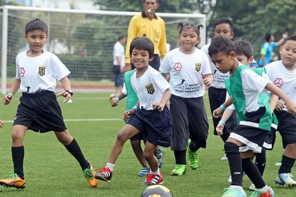 GHAIRAH SERTAI PROGRAM: Kanak-kanak daripada keluarga kurang bernasib baik di Yishun ghairah beraksi dalam Piala Nee Soon yang diadakan sempena pelancaran Program Bola Sepak Sambil Belajar Nee Soon semalam. - Foto THE STRAITS TIMES 