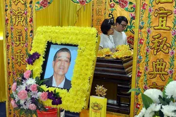 Cik Ong bersama anaknya di sisi keranda Encik Ong Peck Hock pada Rabu (26 Okt). 