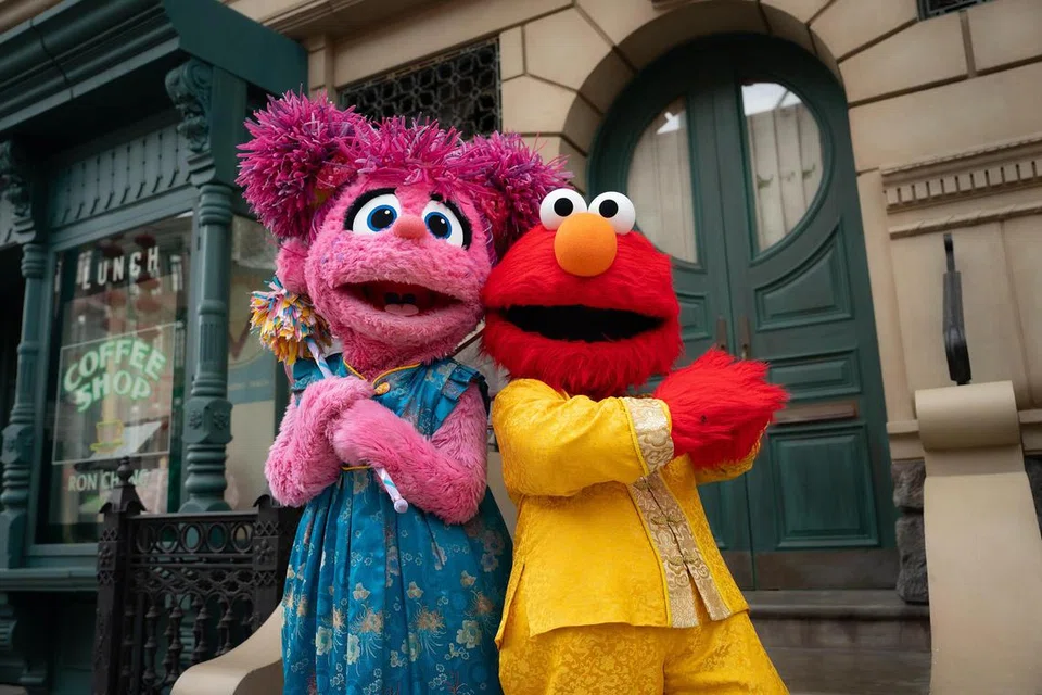 Keluarga boleh juga bergambar bersama watak-watak animasi dari jenama Sesame Street seperti Elmo (kanan) dan Abby Cadabby (kiri) dalam pakaian tradisional Cina semasa berkunjung ke Universal Studios Singapore. 