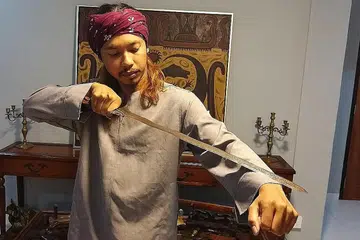 KOLEKSI KESAYANGAN: Encik Abdul Walid menunjukkan sebilah sundang iaitu sejenis senjata orang Melayu dan Moro. Sundang berbentuk seperti keris yang panjang tetapi ia sebenarnya dari jenis pedang. - Foto BH oleh ISMAIL ALI