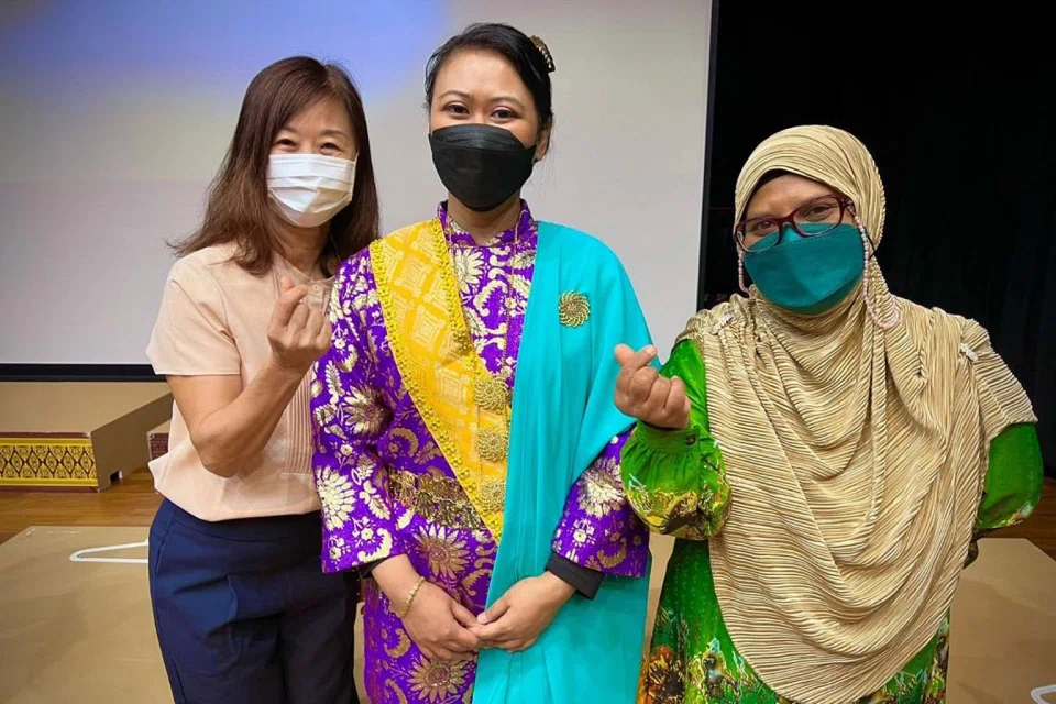 KENALI BUSANA: Peserta bengkel Cik Regina (kiri) dan Cik Nafisah (kanan) diberi peluang menyalinkan pelakon bangsawan Layla Wahid mengenakan busana untuk watak Dang Manjarani. - Foto ANGGERIK TEMASEK BANGSAWAN.