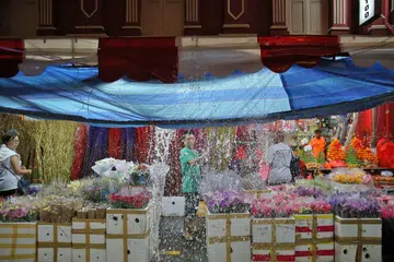 JUALAN MURAM: Seorang peniaga di Temple Street sedang membuang air hujan yang terkumpul di khemahnya ekoran hujan lebat. - Foto THE STRAITS TIMES