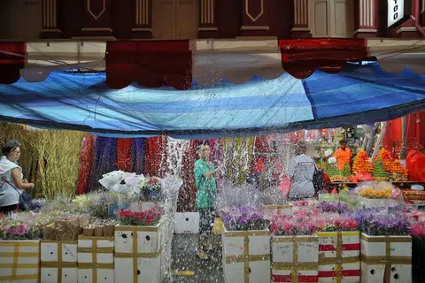 JUALAN MURAM: Seorang peniaga di Temple Street sedang membuang air hujan yang terkumpul di khemahnya ekoran hujan lebat. - Foto THE STRAITS TIMES