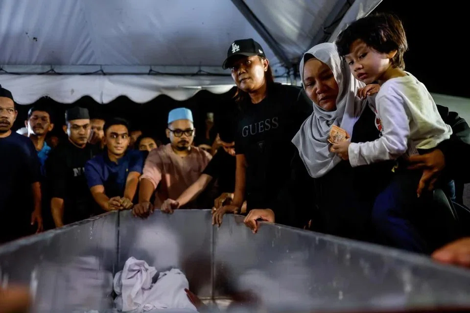 Balu Allahyarham Leftenan Komander Wan Rezaudeen Kamal Wan Zainal Abidin, Cik Aliya Amalina Md Noor, bersama anaknya Wan Alyan Riz Wan Rezaudeen Kamal melihat jenazah suaminya di Tanah Perkuburan Raudhatul Sakinah Kuala Lumpur-Karak, Selangor, sebelum dikebumikan pada 24 April.
