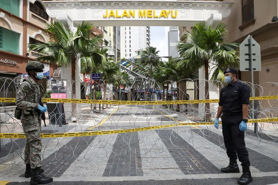 JUMLAH TERENDAH: Seorang askar dan pegawai polis dilihat pada 15 April 2020, sedang menjaga satu 'zon merah' yang dikepung di Kuala Lumpur. - FOTO: REUTERS. 