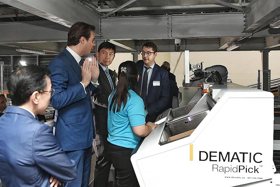 KEMUDAHAN BARU: Satu ciri menarik kemudahan baru Bollores Logistics di Boon Lay ini adalah sistem automasi berpusat yang merangsang produktiviti. Encik Chee Hong Tat (tengah, bertali leher) sedang mendengarkan taklimat mengenai kemudahan tersebut. - Foto BH oleh KHALID BABA