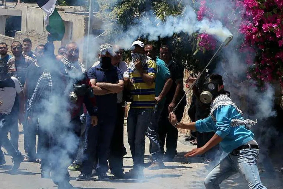 Seorang penunjuk perasaan Palestin membaling kanister gas pemedih mata kembali ke arah pasukan keselamatan Israel semasa pertempuran pada 27 Mei di kampung Kfar Qaddum di West Bank, yang diduduki Israel. 