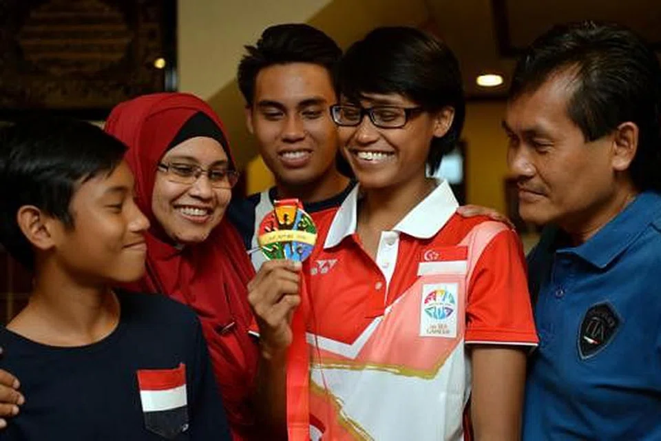 TURUT GEMBIRA: Pingat emas Baizura turut disambut ibu bapanya, Cik Khairon Mansoor (dua dari kiri) dan Encik Abdul Razak Osman (kanan) dan adik-adiknya - Ezrafil Iman (kiri) dan Alif Iskandar (tiga dari kiri). - Foto M.O. SALLEH