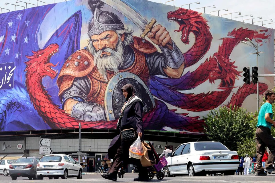 Seorang wanita berjalan melewati lukisan yang menggambarkan adegan daripada epik kebangsaan Iran, Shahnameh, di Tehran pada 5 Ogos 2025.