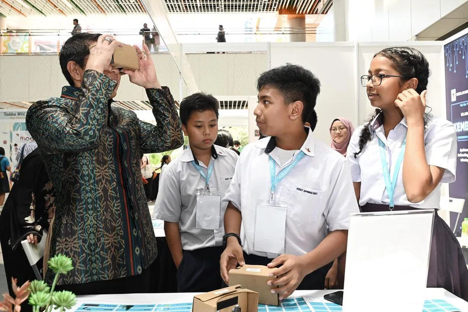 WADAH MENARIK: Pelajar dari Sekolah Menengah West Spring (dari kanan), Aleesya Syuhada Mohamad Faizal Ali, Qarman Armanie Mohammad Faizal dan Muhammad Lutfil Hadi Moharum, menunjuk Menteri di Pejabat Perdana Menteri dan Menteri Kedua (Ehwal Luar merangkap Pendidikan), Dr Mohamad Maliki Osman, yang juga pengerusi Pembelajaran dan Penggalakan Penggunaan Bahasa Melayu (MLLPC) permainan realiti maya (VR) yang menggalakkan pengunaan bahasa Melayu.