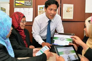 MUDAH DAN RINGKAS: Encik Izman Osman, Pengarah Pembangunan Perniagaan dari Pytheas, menerangkan kepada kakitangan Shahidah Travel mengenai penggunaan tempahan dan pembayaran dalam talian. - Foto KHALID BABA