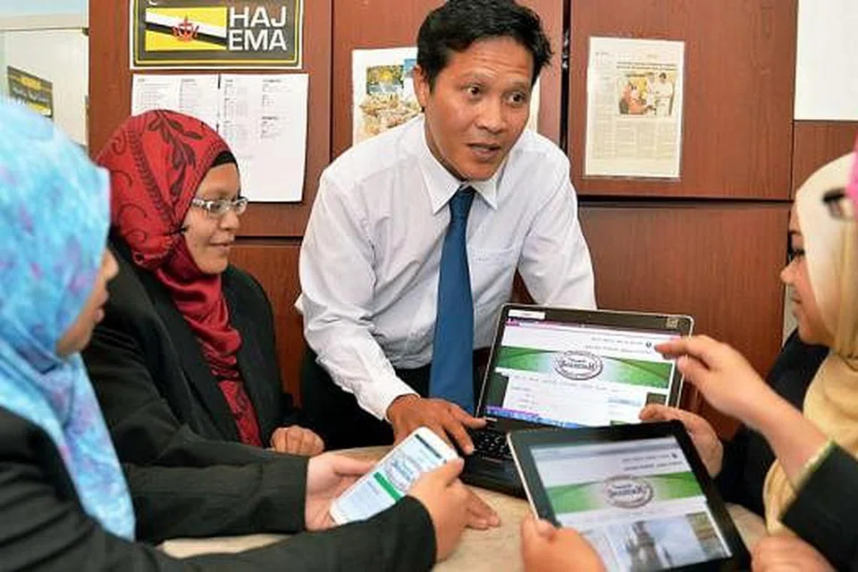 MUDAH DAN RINGKAS: Encik Izman Osman, Pengarah Pembangunan Perniagaan dari Pytheas, menerangkan kepada kakitangan Shahidah Travel mengenai penggunaan tempahan dan pembayaran dalam talian. - Foto KHALID BABA