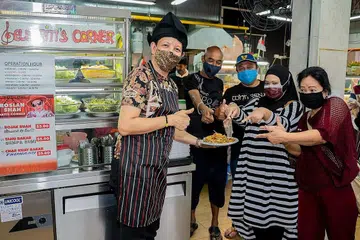 BIJAK AMBIL HATI PEMINAT: Sejak Julai lalu, penghibur setempat, Roslan Shah, mengendalikan gerai rojak buah, tahu bakar dan char kuay bakar di Kedai Kopi Al Ikhlas sekitar 60 Lorong 101 Changi yang menarik peminatnya yang senangi keramahan dan keenakan sajian yang dihidangkan. - Foto NUR DIYANA TAHA