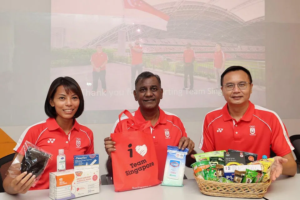 SEDIA BERSAING: Cef-de-mission Team Singapore di Sukan SEA Hanoi, S. Sinnathurai (tengah, gambar atas) dengan dua penolongnya, Asmah Hanim dan Damien Ler bergambar bersama pek penjagaan yang akan diberikan kepada atlet dan pegawai Singapura. - Foto LIANHE ZAOBAO