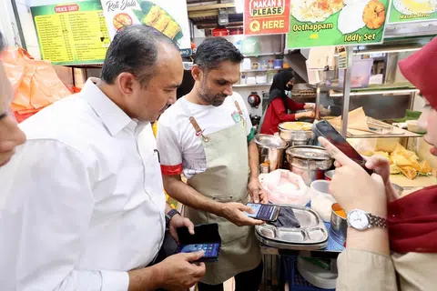 Pengerusi Jawatankuasa Perumahan dan Kerajaan Tempatan Johor, Datuk Mohd Jafni Md Shukor (kiri), melihat penggunaan baucar Majlis Pembangunan Masyarakat (CDC) ketika lawatan kerja ke Pasar Geylang Serai, Singapura.