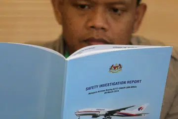 LAPORAN MH370: Seorang anggota keluarga penumpang penerbangan MH370 membaca laporan itu sebelum satu taklimat tertutup di Putrajaya, Malaysia pada 30 Julai 2018. 