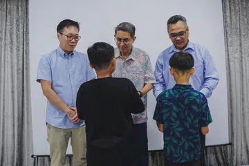 Profesor Madya Dr Muhammad Faishal Ibrahim (tengah) bersama Encik Wong Wei Kong (kiri) dan Encik Nazry Mokhtar menyampaikan hadiah baju Raya kepada kanak-kanak Rumah Kebajikan Muhammadiyah.