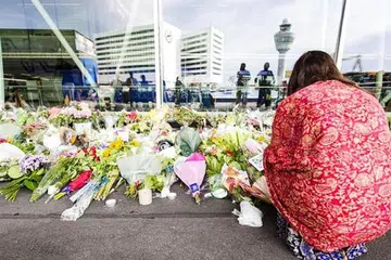 TERUS MERATAPI: Seorang wanita berlutut di tapak peringatan di Lapangan Terbang Schiphol, dekat Amsterdam. - Foto AFP.