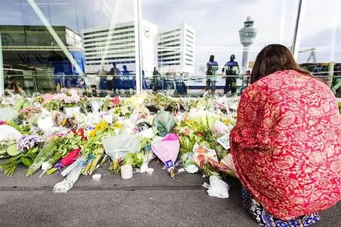 TERUS MERATAPI: Seorang wanita berlutut di tapak peringatan di Lapangan Terbang Schiphol, dekat Amsterdam. - Foto AFP.