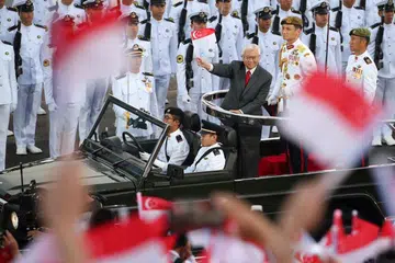 KALI TERAKHIR PERIKSA KAWALAN KEHORMATAN: Presiden Tony Tan mengibarkan bendera kepada penonton semasa pandu lalu selepas memeriksa barisan kawalan kehormatan. - Foto THE STRAITS TIMES