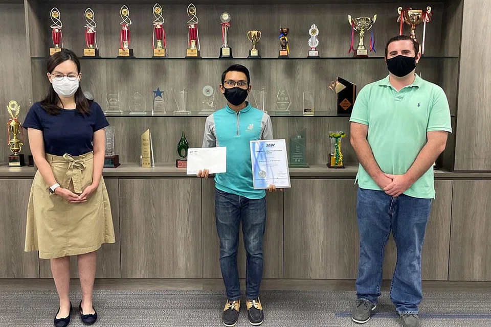 TERIMA PENGHARGAAN: Encik Haziq Taha (tengah), penghantar Deliveroo telah diiktiraf sumbangannya membantu memadamkan api di Pasir Panjang Road bulan lalu oleh Pasukan Pertahanan Awam Singapura (SCDF). Beliau menerima Anugerah Responden Pertama Masyarakat. Bersama dalam gambar adalah Anggota Parlimen GRC West Coast Cik Rachel Ong (kiri) dan Ketua Operasi Deliveroo Singapura, Encik Jason Parke (kanan). - Foto SCDF