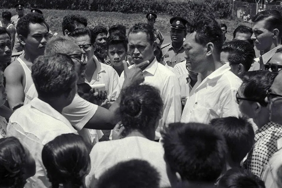 MENENANGKAN KEADAAN: Encik Othman (baju putih, tengah gambar) dan Perdana Menteri Pengasas Lee Kuan Yew (di sebelahnya) melawat pemimpin masyarakat di serata Singapura untuk menenangkan keadaan, pada 24 Julai 1964. - Foto fail