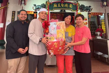 Pegawai Dakwah Masjid Darussalam, Ustaz Shakir Zamri (kiri), dan Pegawai Pembangunan Masyarakat Masjid Darussalam, Ustaz Hariz Ramli (dua dari kiri), memberi habuan berisi pelbagai barang makanan kepada kakitangan kuil Ang Chee Sia Ong sempena Tahun Baru Cina pada 28 Januari.